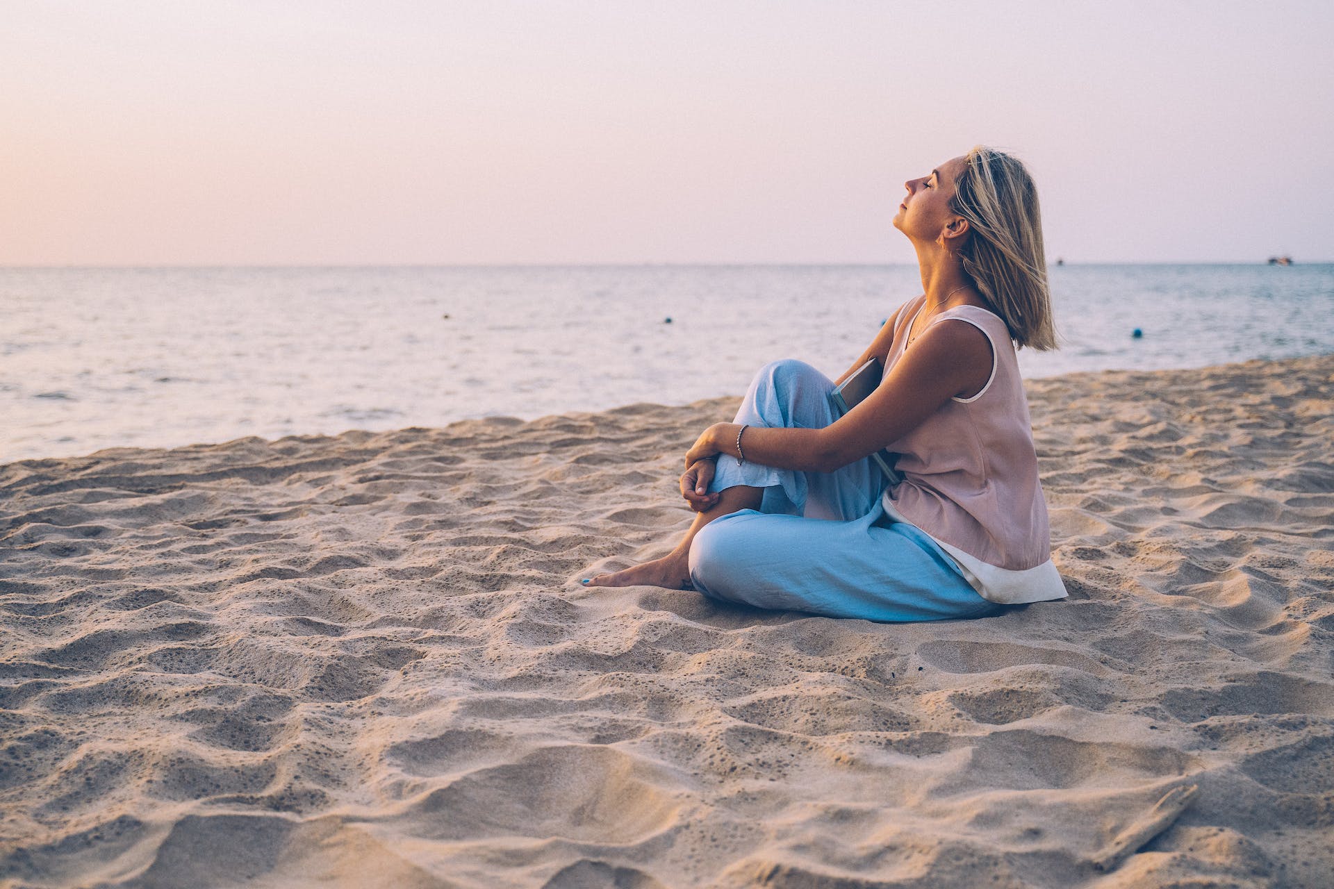 Woman sitting on a beach thinking about OCD and intrusive thoughts.