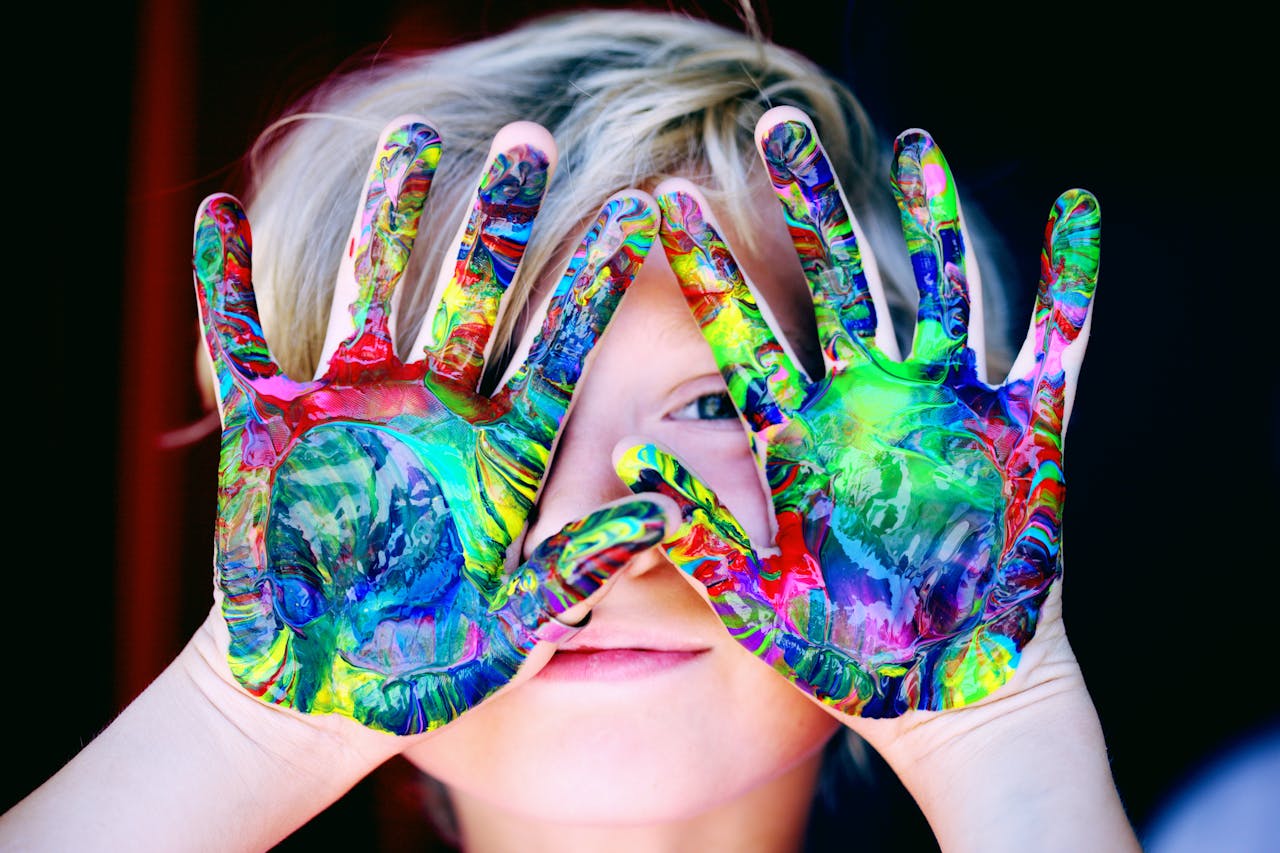 A young person representing the inner child with painting colors on their hands.