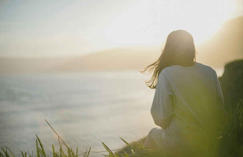 Person sitting on oceanside cliff thinking about stress counseling in Seattle.