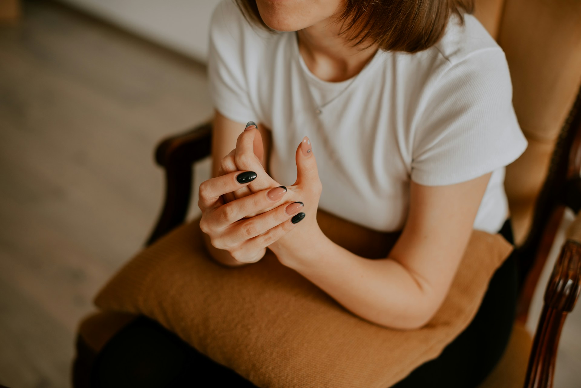 Person sitting in a chair holding their hands together, thinking about mental health stigma within healthcare.