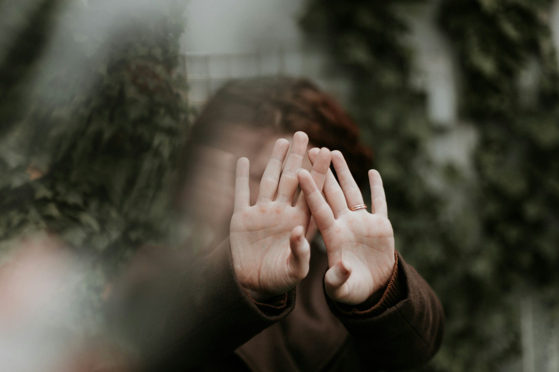 Person covering their face with their hands, representative of neurodivergent masking